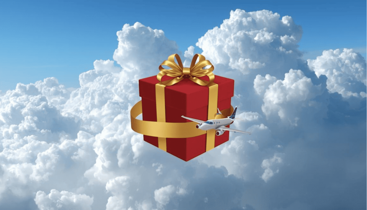 Fondo de nubes y en el medio iuna caja de regalo roja con lazo dorado envuelto por un avión.